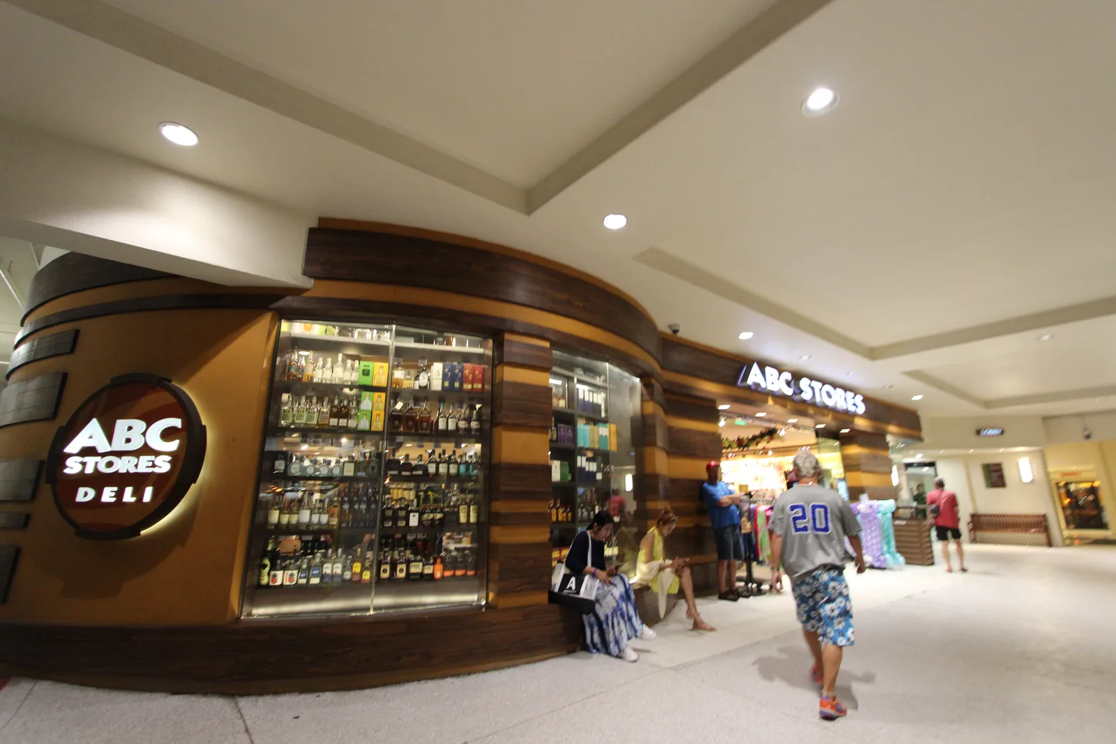 ショッピングモールの通路に面したABCストアの店舗。入口の横に「ABC STORES DELI」の看板とお酒の並ぶショーケースがある