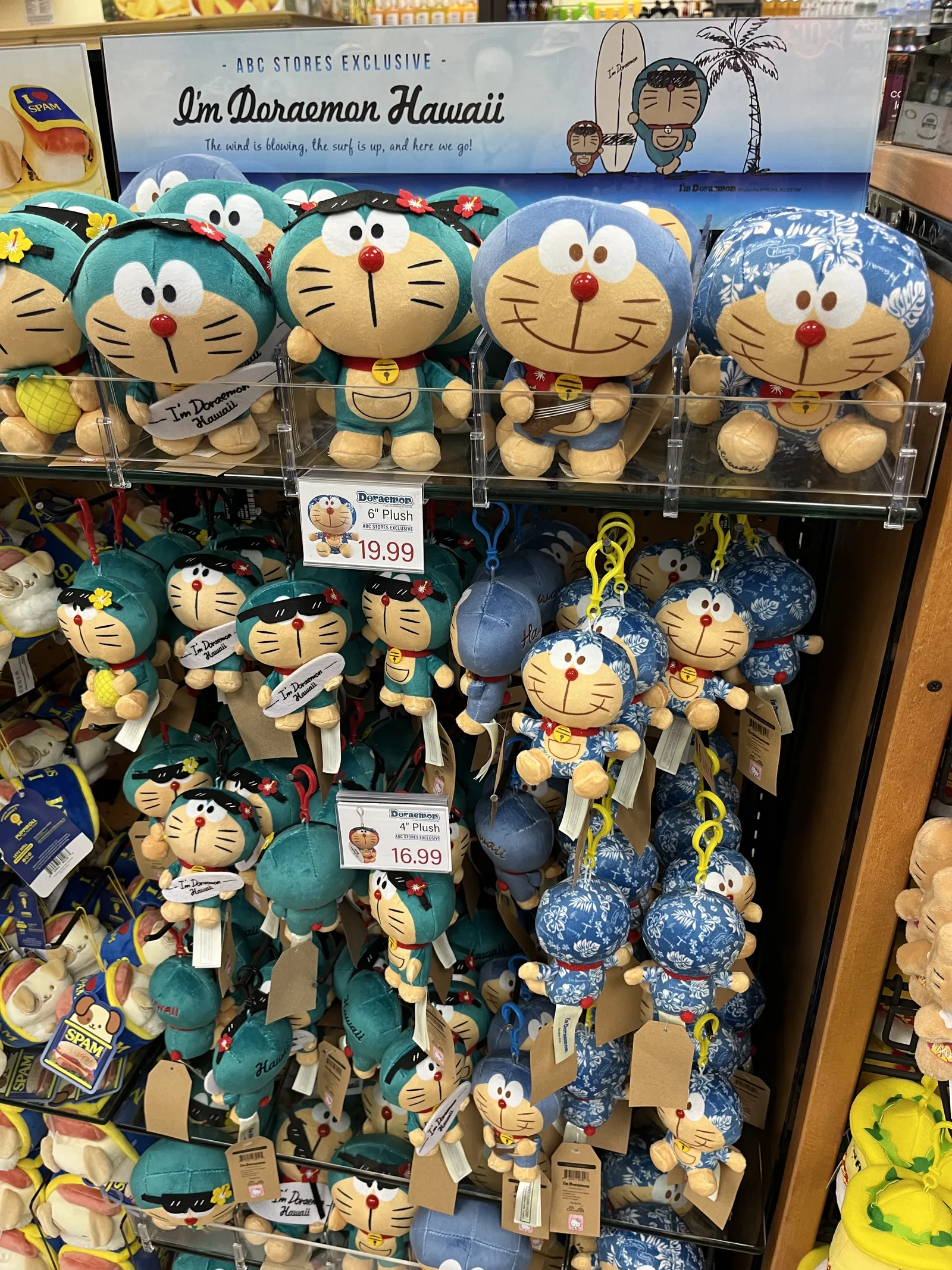 「I'm Doraemon Hawaii」の看板の下に、花の髪飾りやアロハ柄の服を着たドラえもんのぬいぐるみが並んでいる