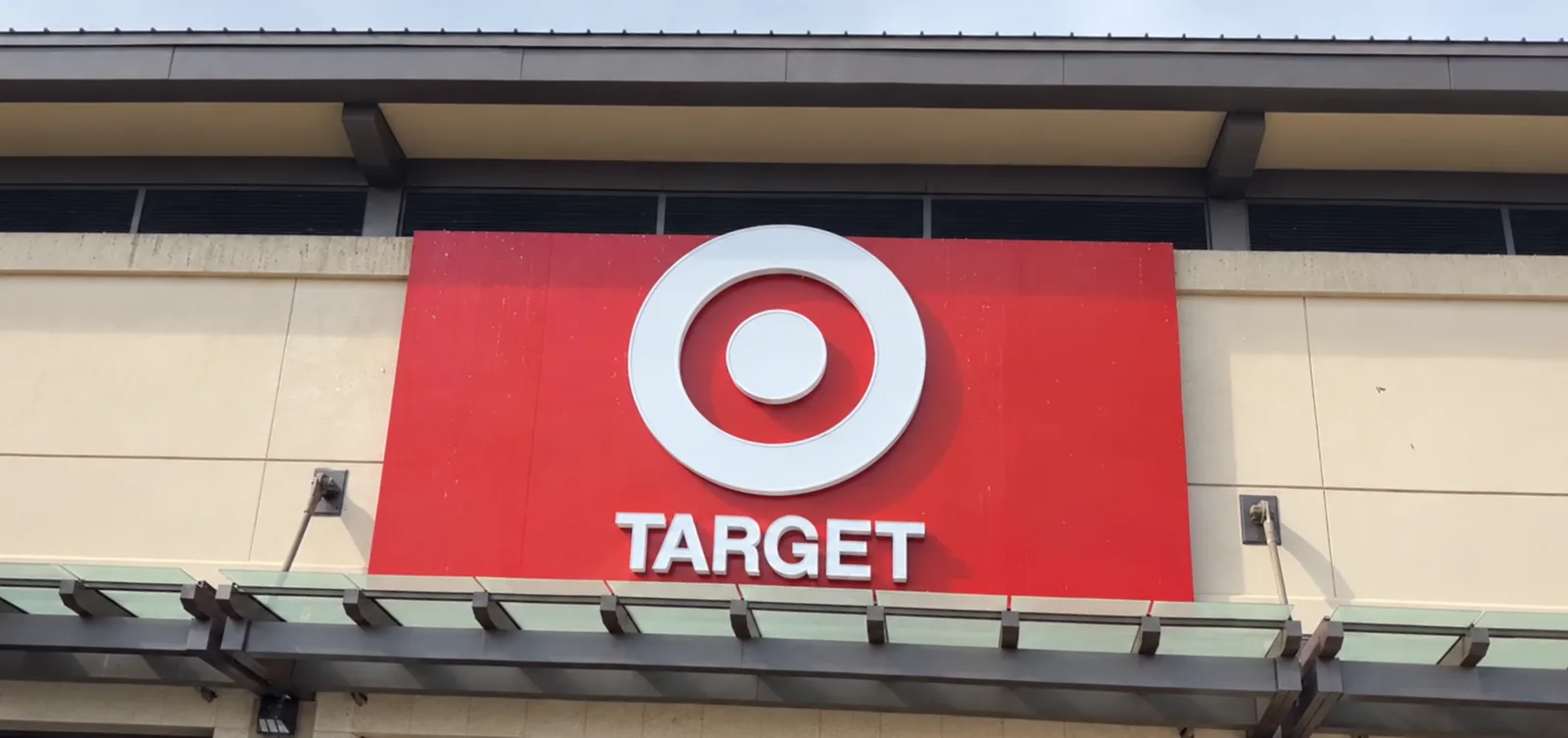 赤い看板に白い丸のロゴと「TARGET」の文字。ベージュの外壁とガラスのひさしの上に掲げられている