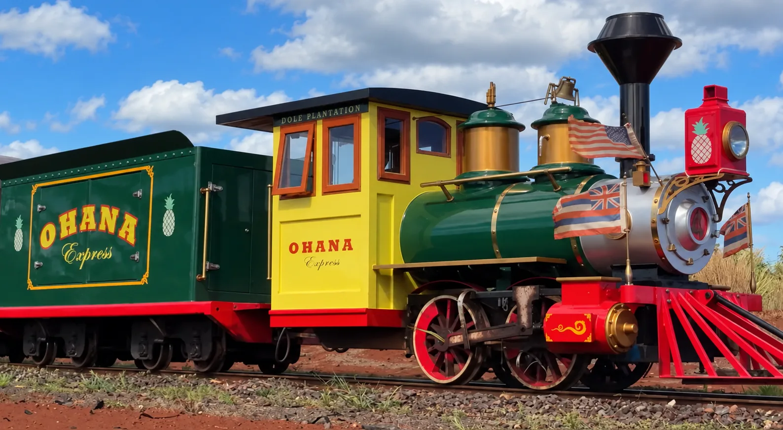 黄色い運転室と緑のボイラーの小さな蒸気機関車。車体に「OHANA Express」の文字、前にはアメリカとハワイの旗