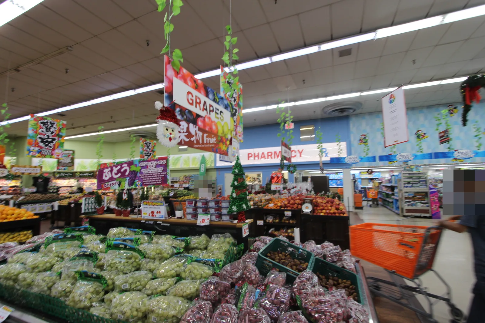ぶどうが山積みの青果売り場の奥に「PHARMACY」の看板が見える