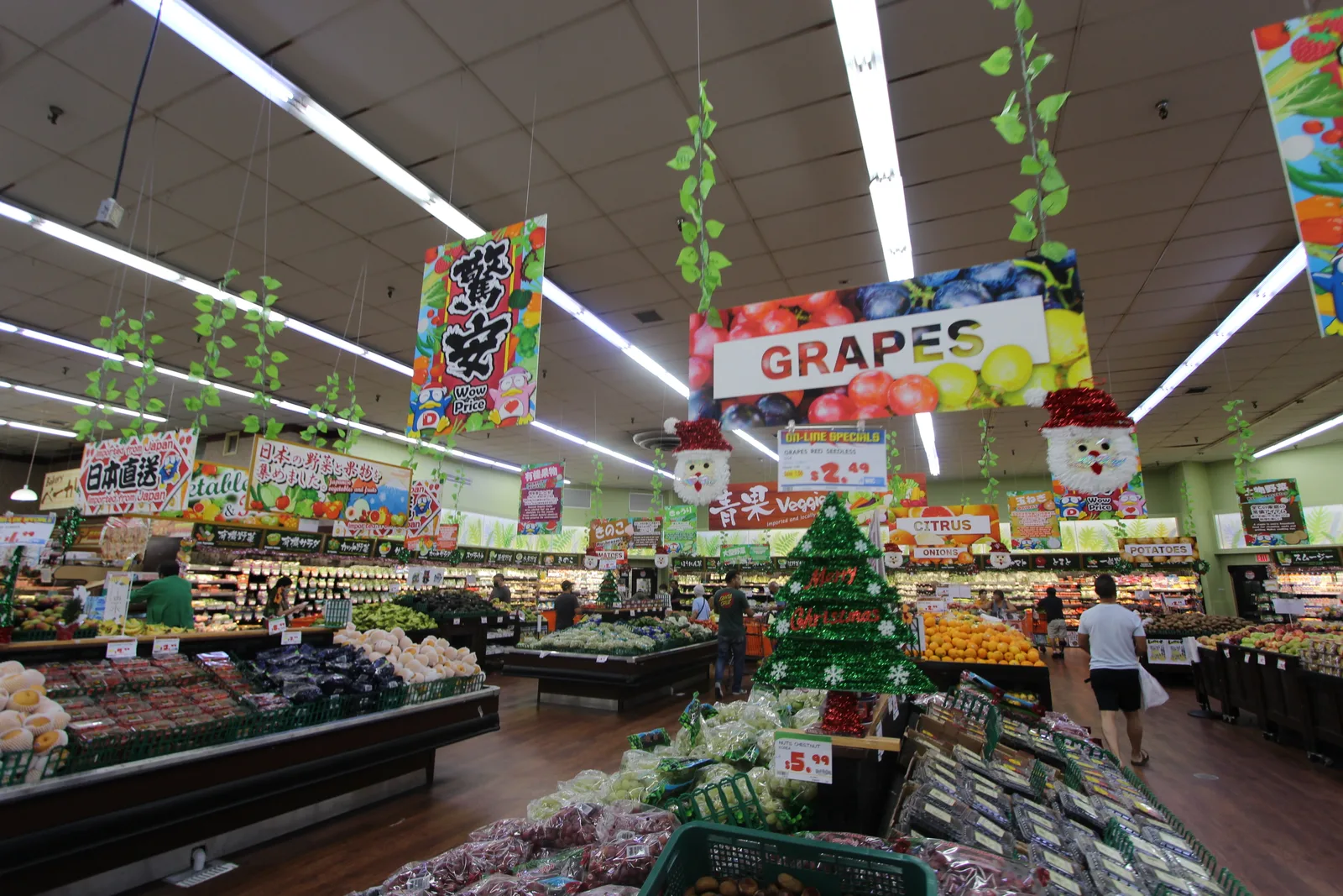 「GRAPES」の看板やクリスマスツリーの飾りの下に、果物や野菜が並ぶ広い青果売り場