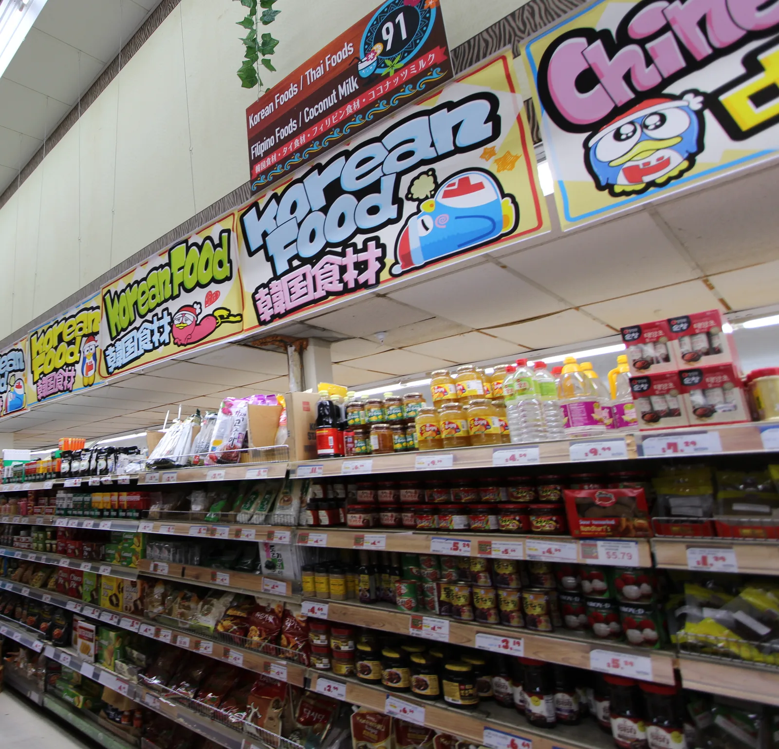 「Korean Food 韓国食材」の看板の下に、韓国の調味料や食品が並ぶ棚