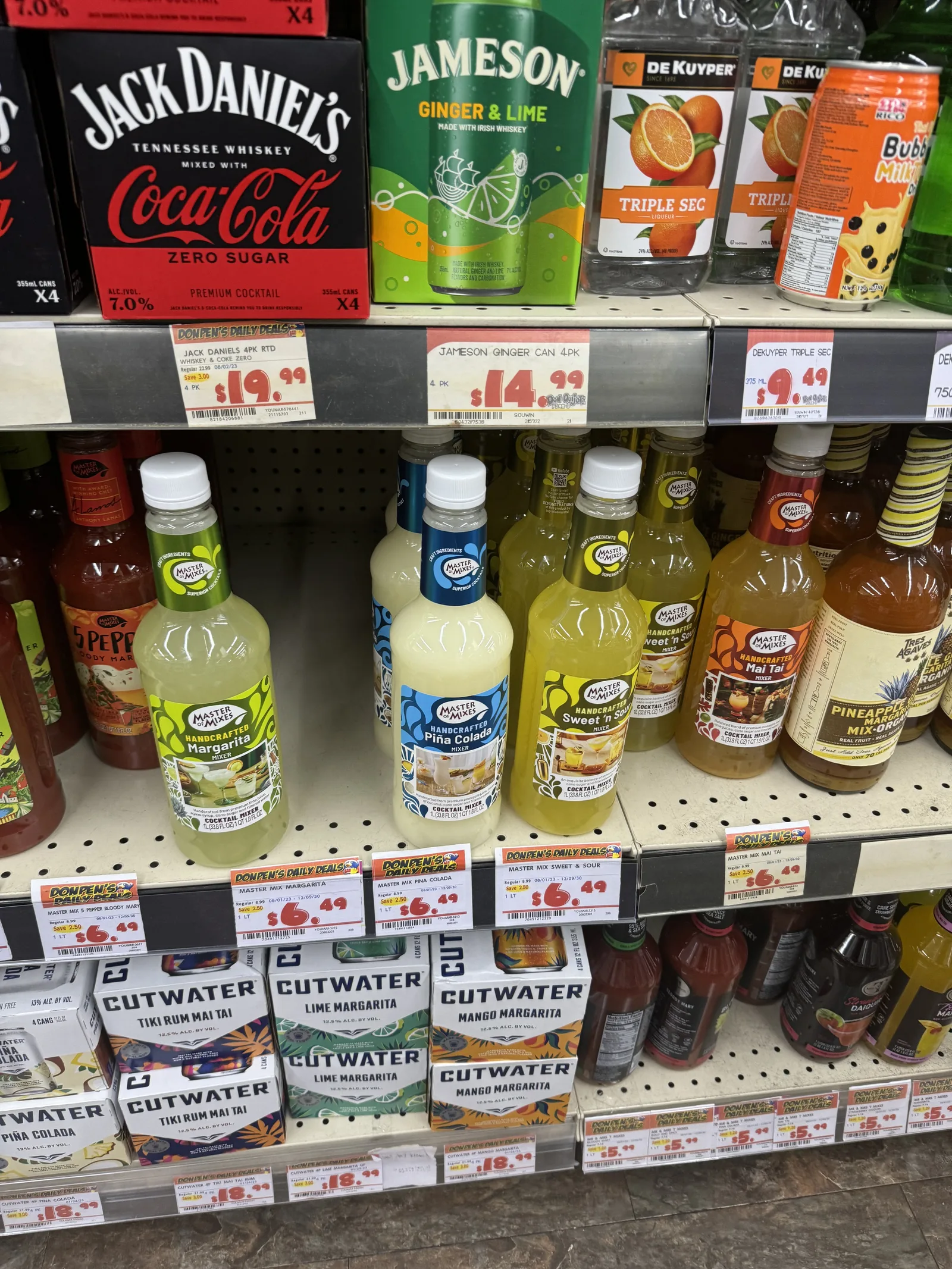 ジャックダニエル&コカ・コーラの缶の4本パックが19.99ドル、ジェムソンの缶カクテルが14.99ドルの値札で並び、下の段にカクテルミックスのボトルがある