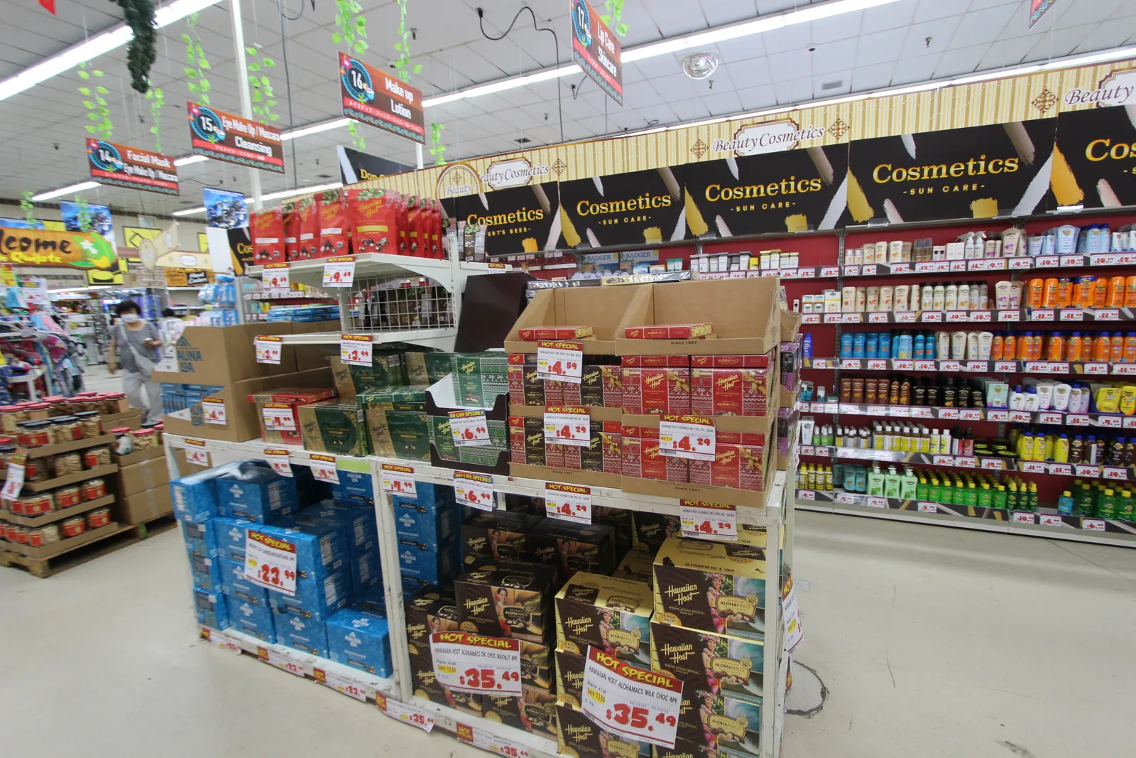 「Cosmetics」の看板が続く通路と、手前の島にチョコの箱やコスメが積まれた売り場