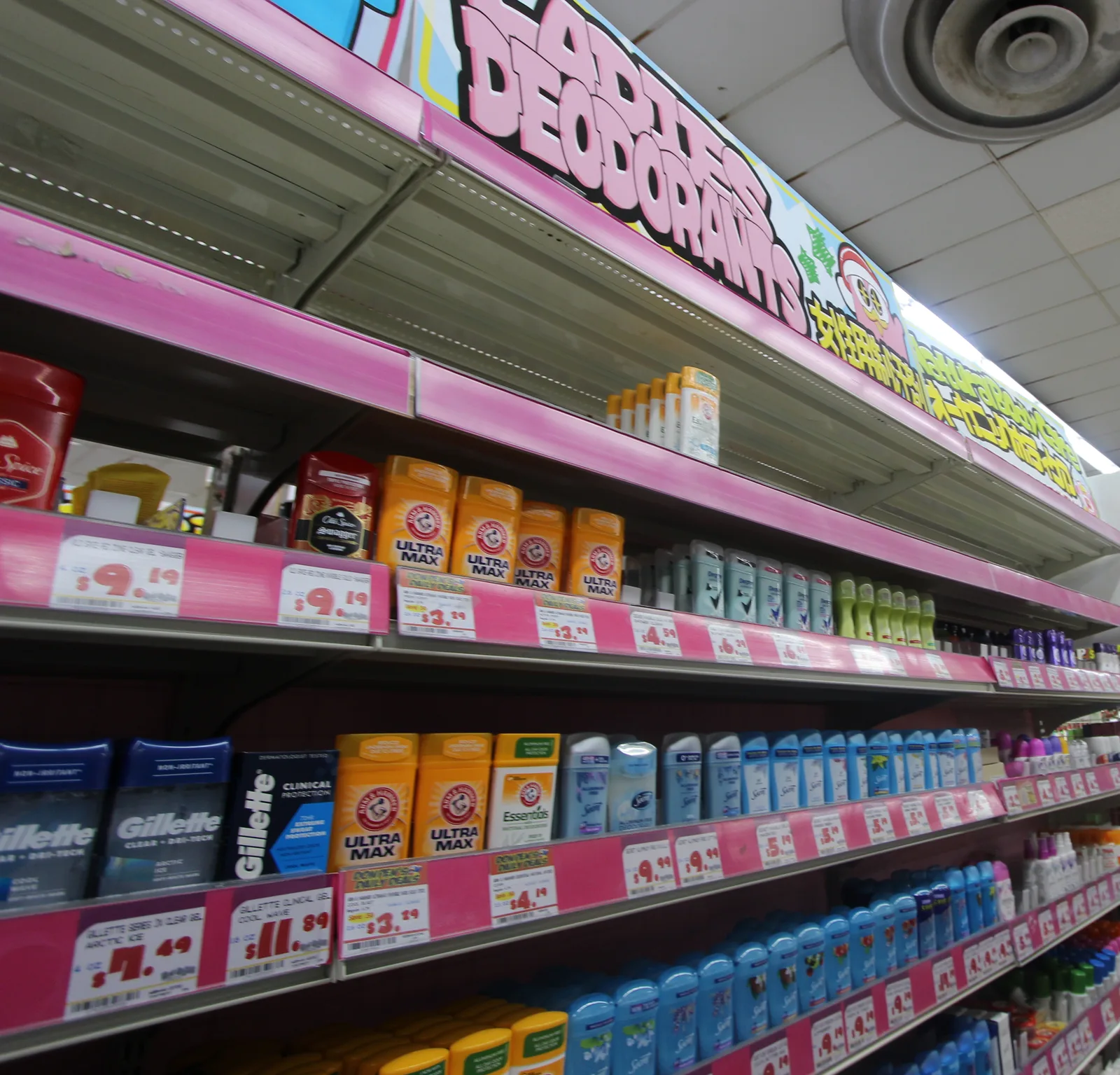 「LADIES DEODORANTS」の看板の下に、デオドラントのスティックが並ぶピンクの棚