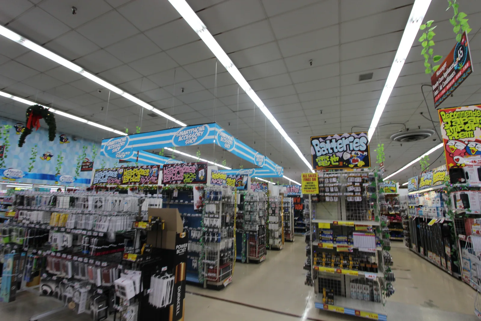 「Batteries 電池」の看板や、スマートフォンのケーブルや充電器が掛かった売り場