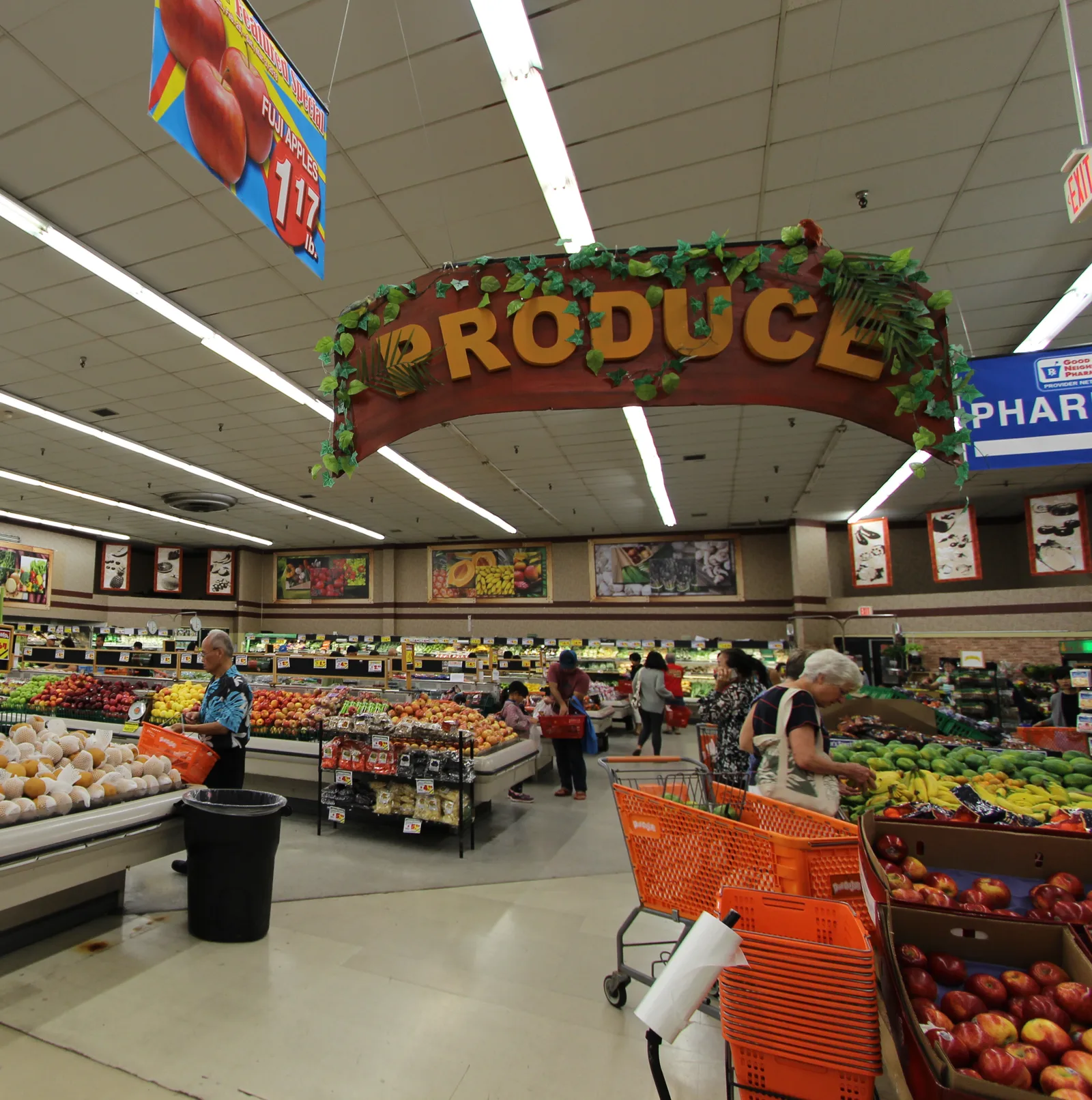 「PRODUCE」の看板の下に、りんごやバナナなどの果物が並ぶ青果売り場