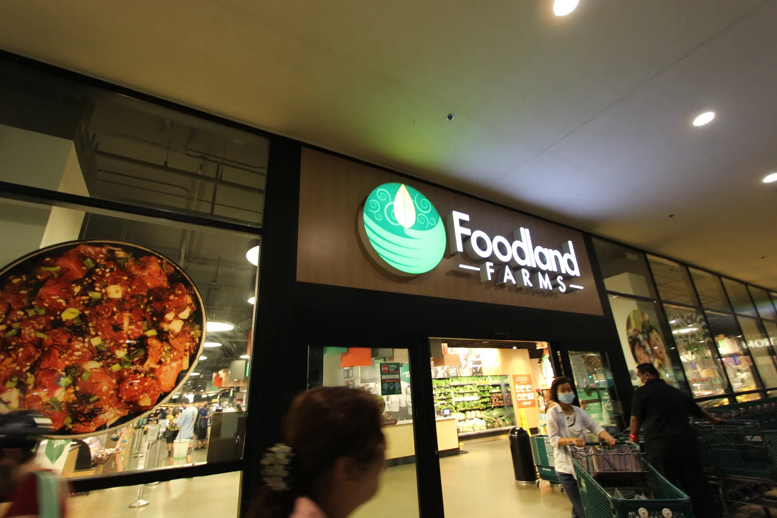 「Foodland FARMS」のロゴが掲げられた店の入口と、ポケの写真が大きく飾られたガラス窓