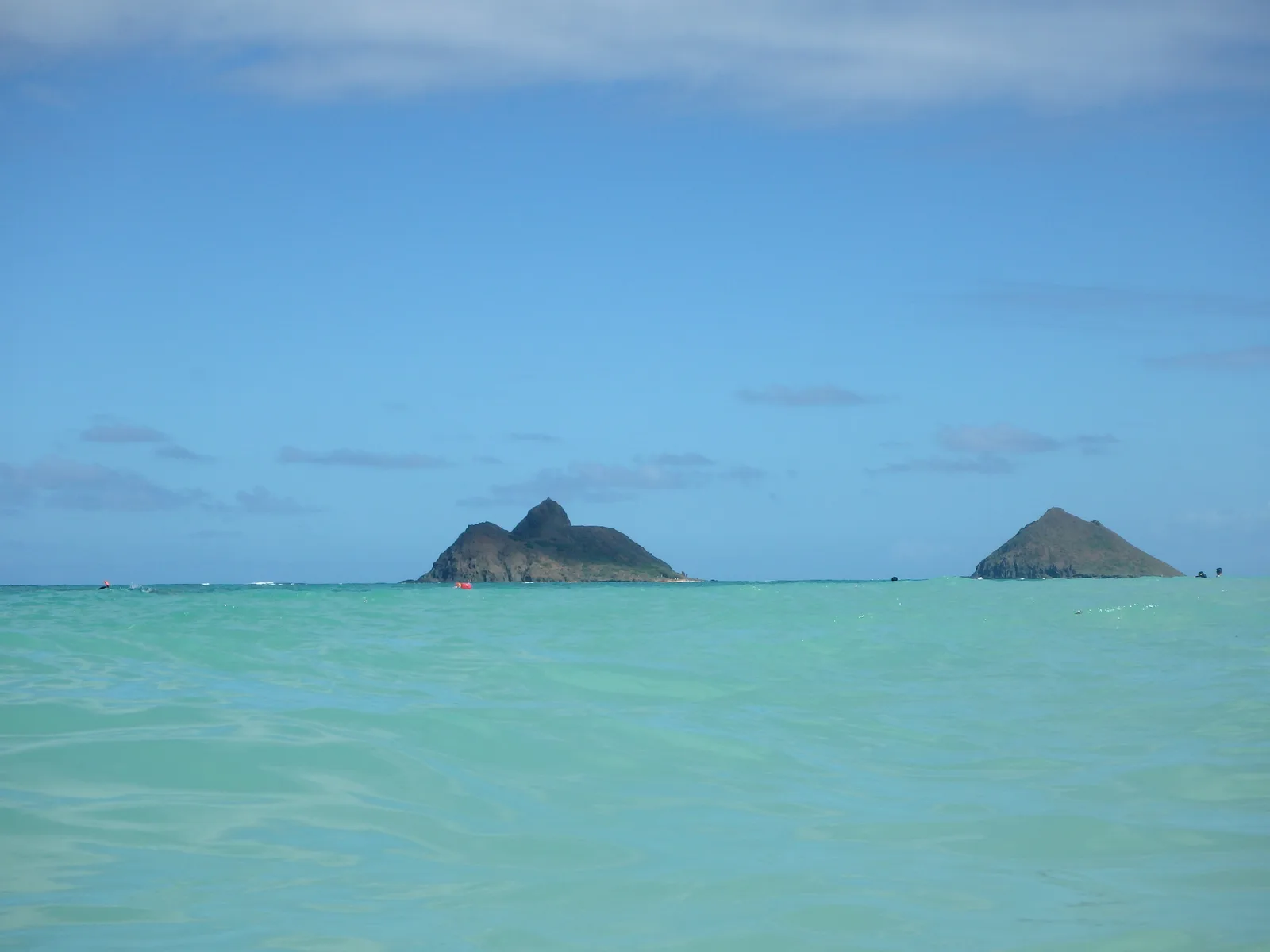 エメラルドグリーンの海の沖に、2つの小さな島が並んで浮かんでいる
