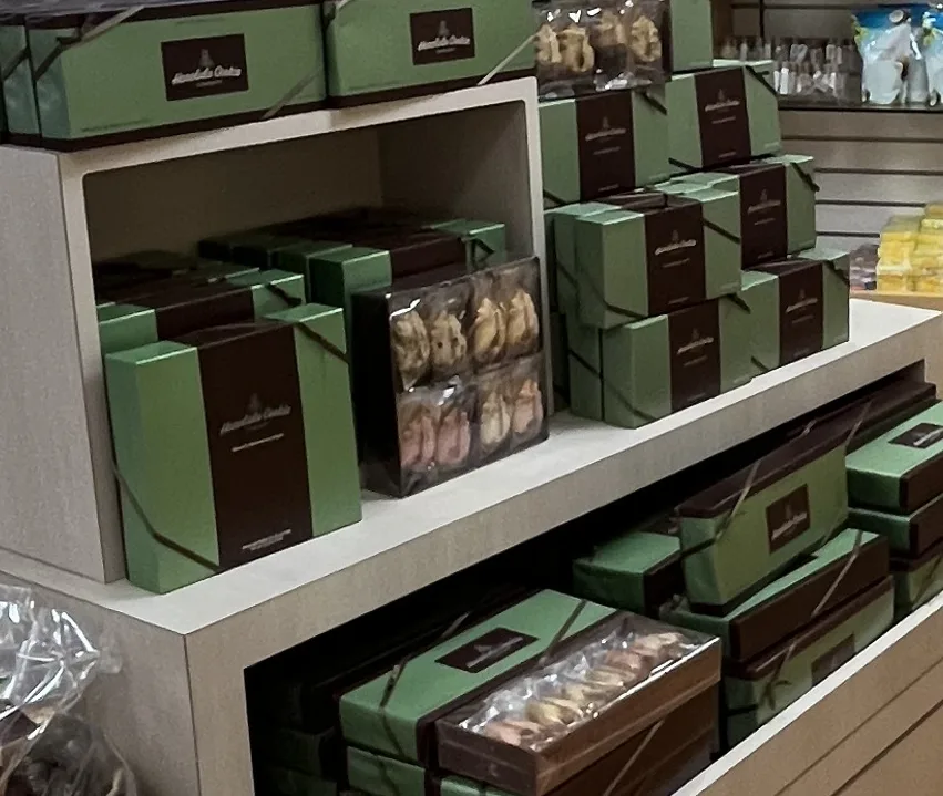 緑と茶色のホノルル・クッキー・カンパニーの箱が棚に積まれ、透明な箱の中にパイナップル形のクッキーが見えている