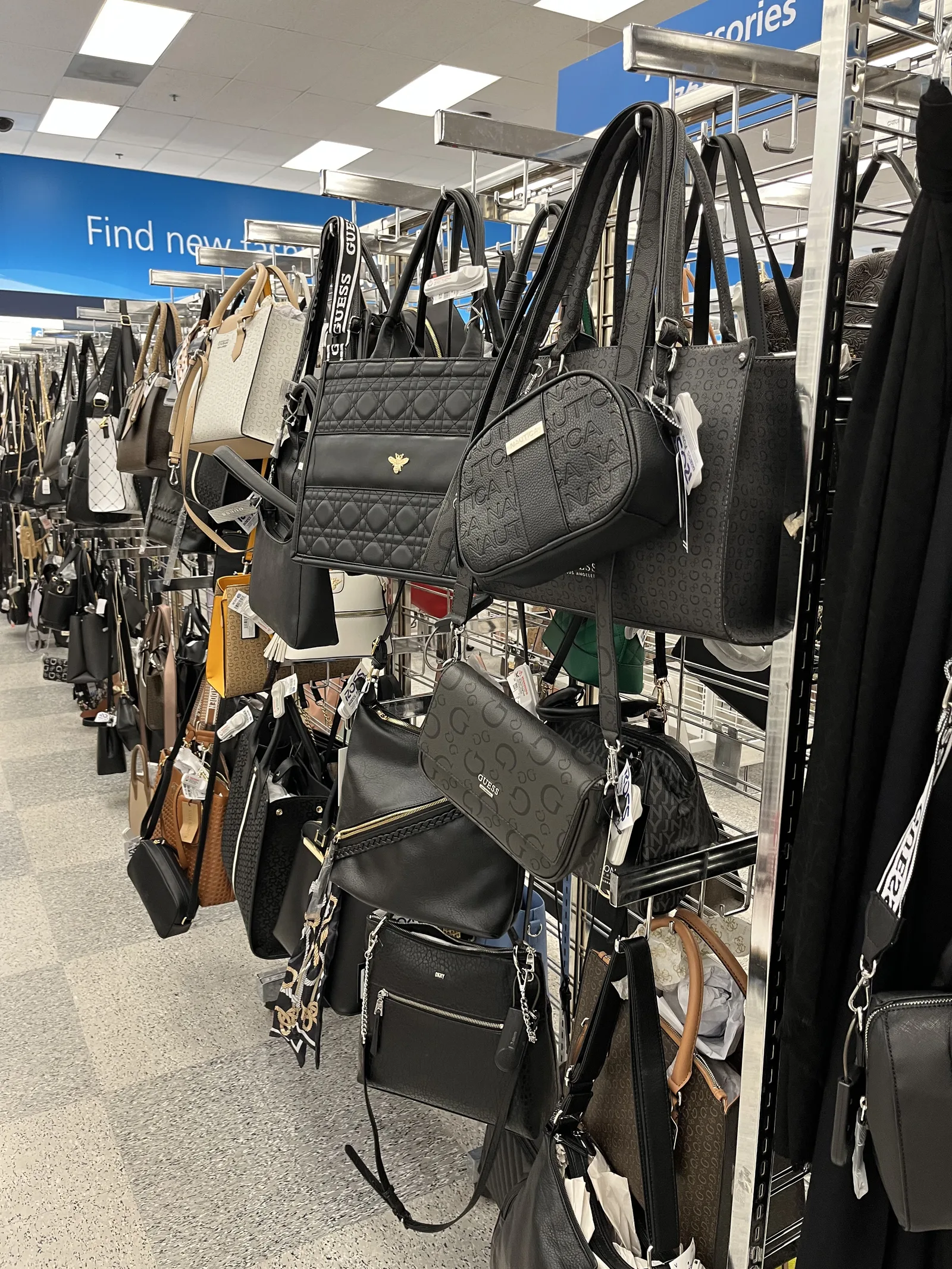 ラックにゲス、ノーティカ、DKNY などのロゴが入った黒やベージュのハンドバッグがずらりと掛かっている