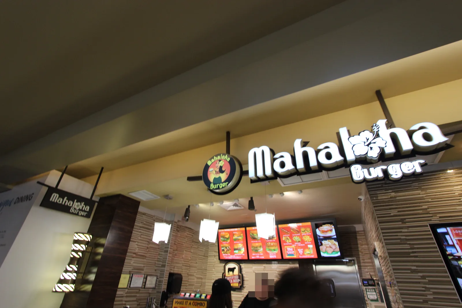 「Mahaloha Burger」のロゴ看板の下に、写真付きのメニュー画面が並ぶ注文カウンター