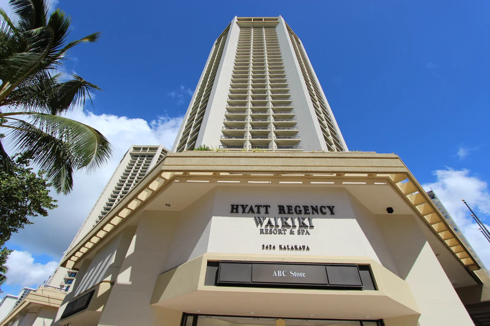 HYATT REGENCY WAIKIKIの文字がある入り口の上にそびえる高層タワー。1階にABCストアの看板