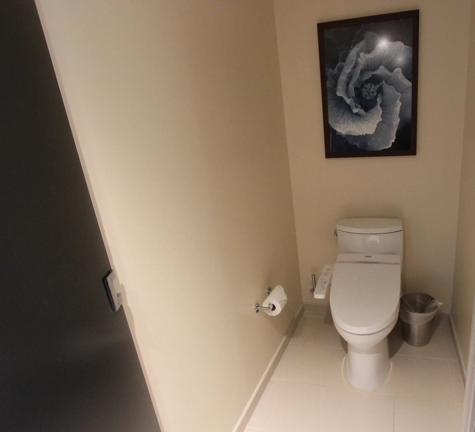 白いタイルの個室トイレに、操作パネルが横についた温水洗浄便座が置かれている